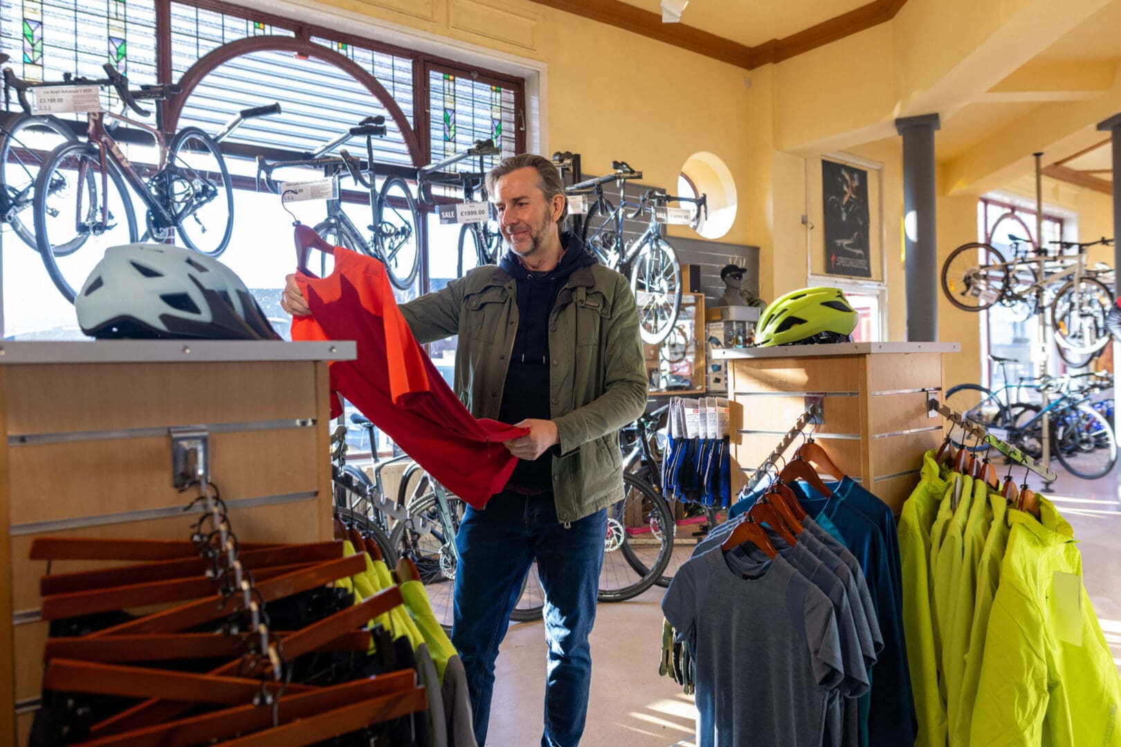 A man shopping for a red sweater in a bike shop.