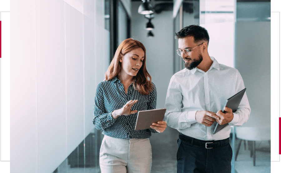 Two colleagues discussing work using a digital tablet in an office.